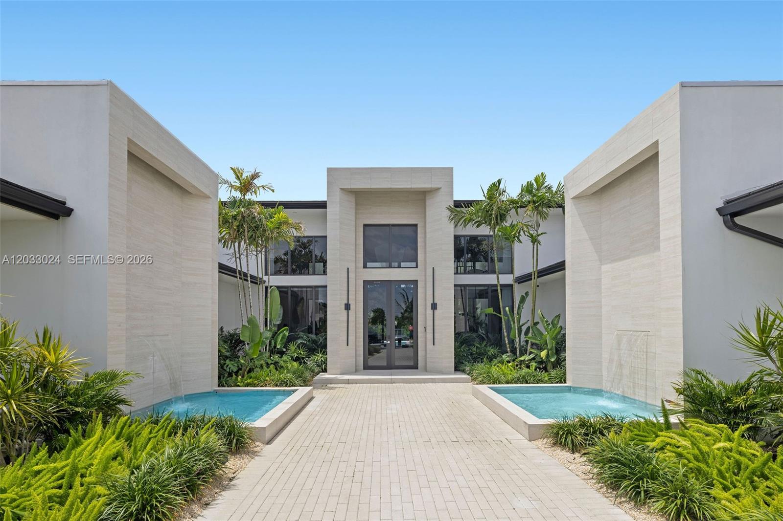 A modern house exterior features a paved walkway between two symmetrical reflecting pools and fountains — 14910 SW 16th Ct, Davie FL 33326, DAVIE, FL