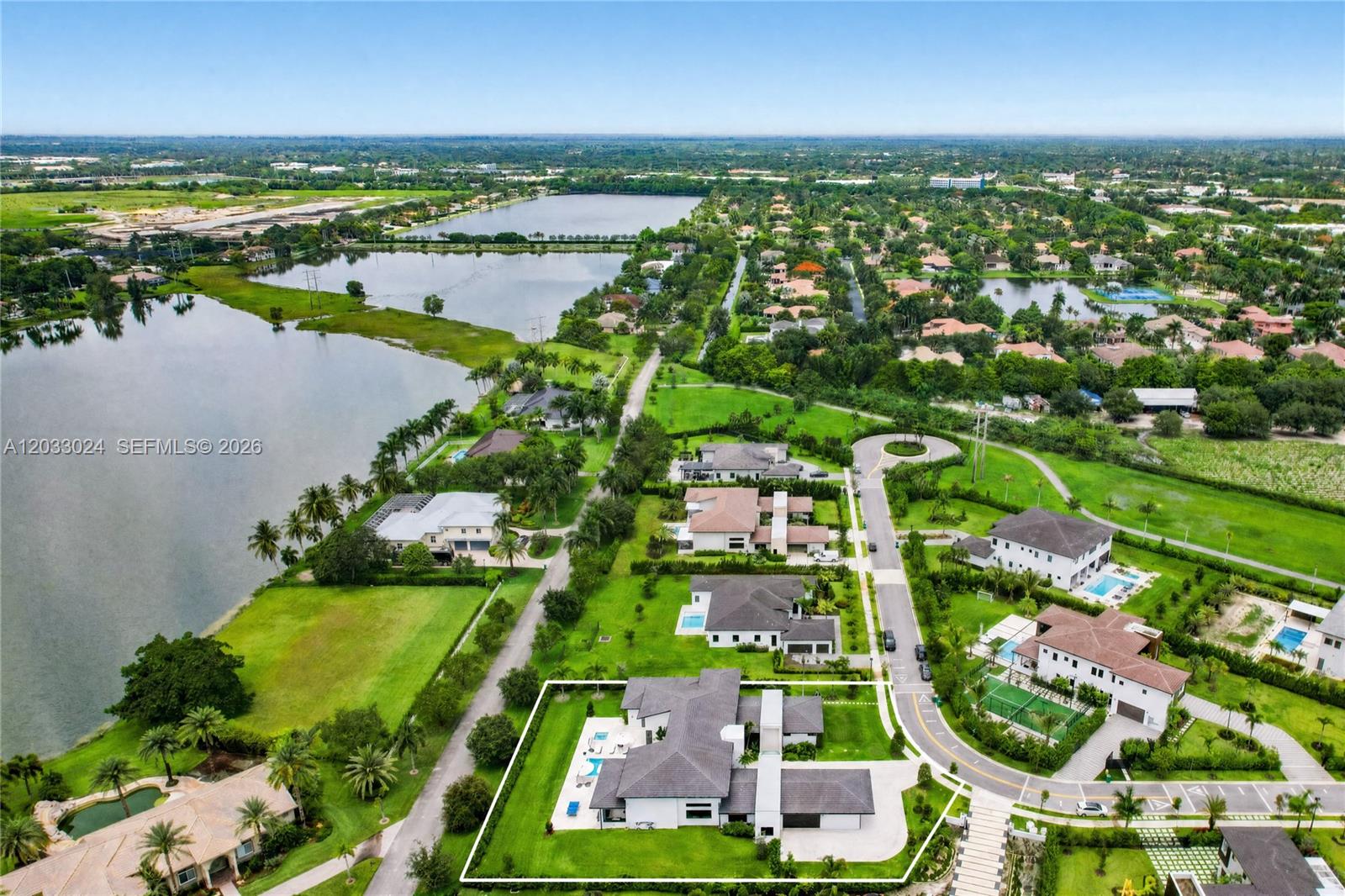 An aerial view shows a modern house with a pool in a suburban lakeside community — 14910 SW 16th Ct, Davie FL 33326, DAVIE, FL