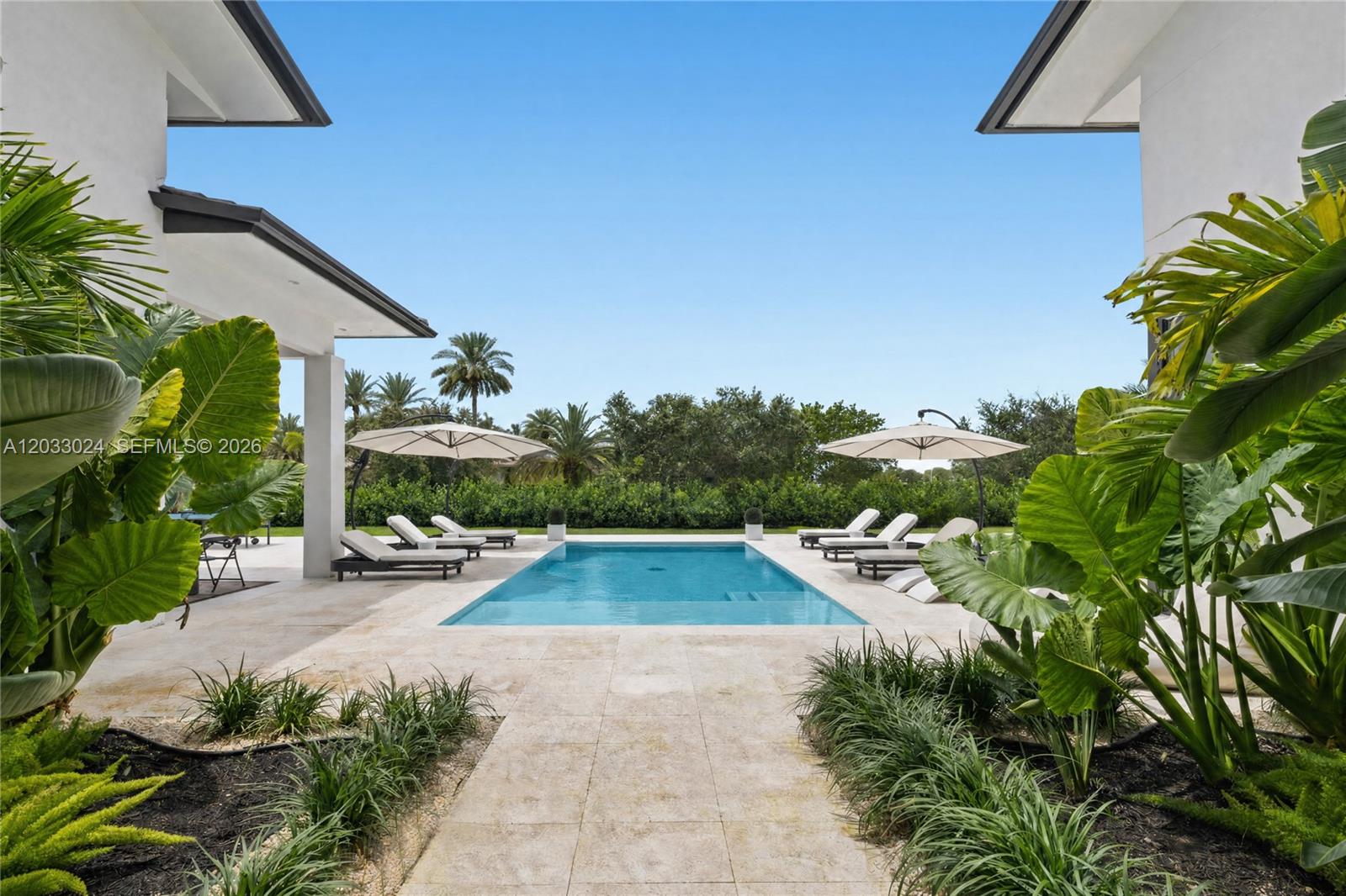 A rectangular swimming pool is centered between two patio areas with lounge chairs and umbrellas — 14910 SW 16th Ct, Davie FL 33326, DAVIE, FL