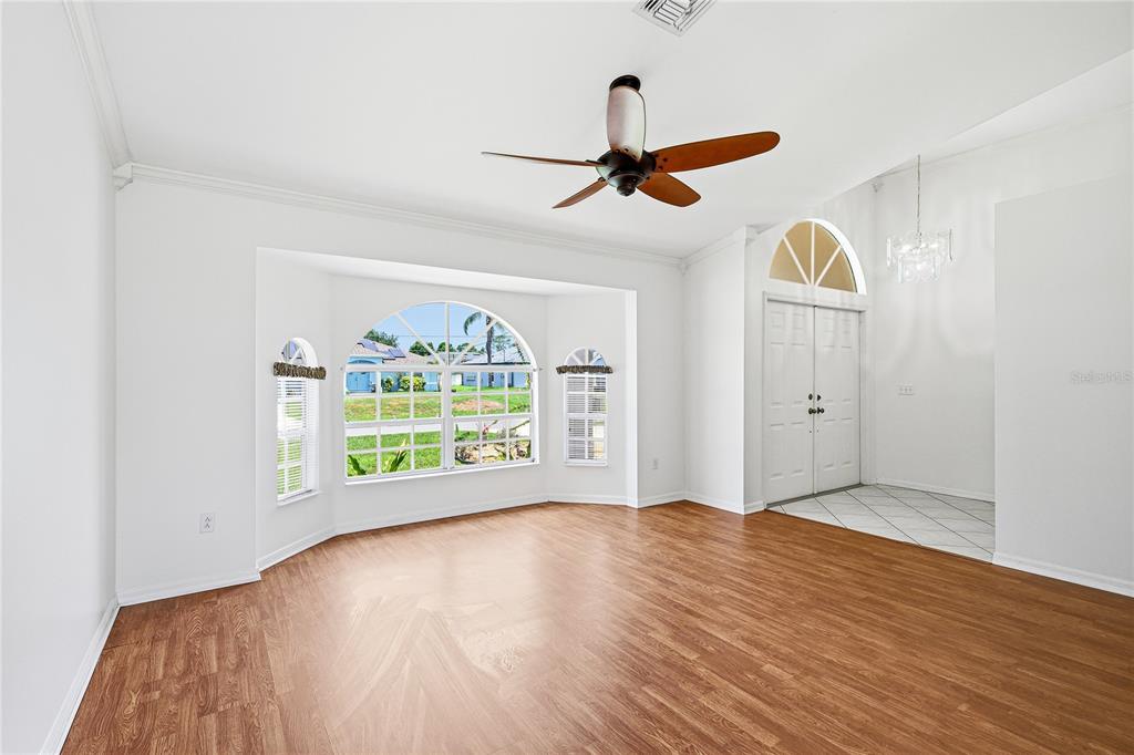 A bright living room features wood-look flooring, a ceiling fan, and a large arched window — 4042 DULUTH TERRACE, NORTH PORT, FL