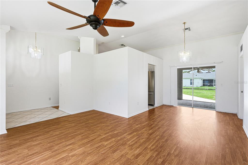 An open-concept living area features wood-look flooring, a ceiling fan, and sliding glass doors — 4042 DULUTH TERRACE, NORTH PORT, FL