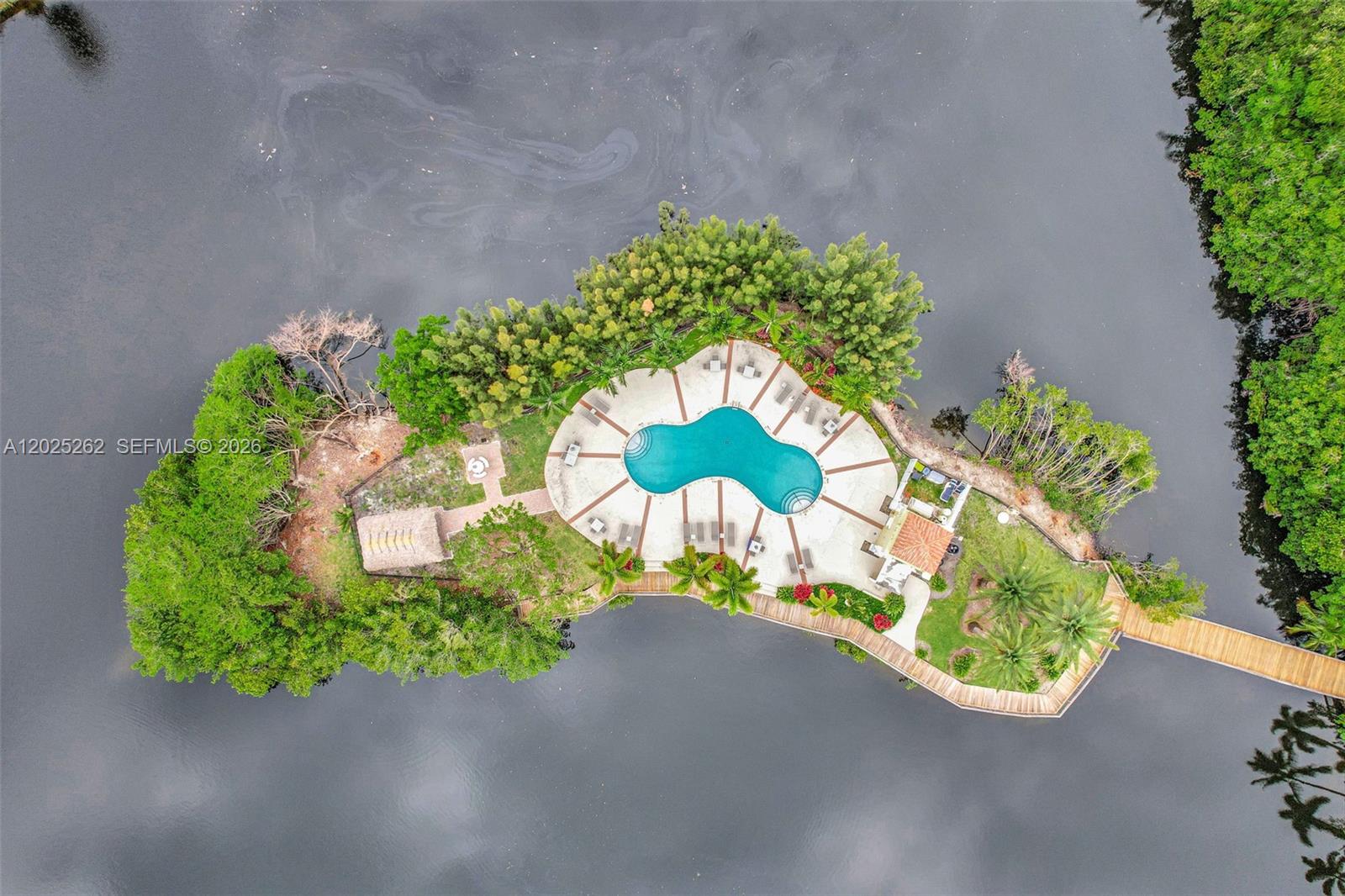 An aerial view shows a private island featuring a swimming pool, deck, and wooden walkway — DANIA BEACH, FL