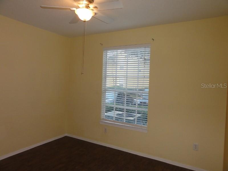 A bedroom with yellow walls, dark wood-look flooring, a ceiling fan, and a window — 830 GRAND REGENCY POINTE UNIT 103, ALTAMONTE SPRINGS, FL