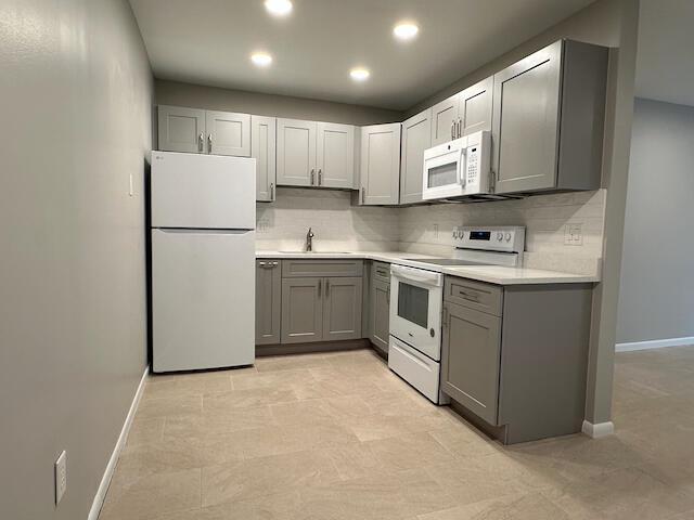 A kitchen features gray cabinets, white appliances, light countertops, and neutral tile flooring — 1741 N 3rd Ave Avenue N # 6, FL 33460, FL