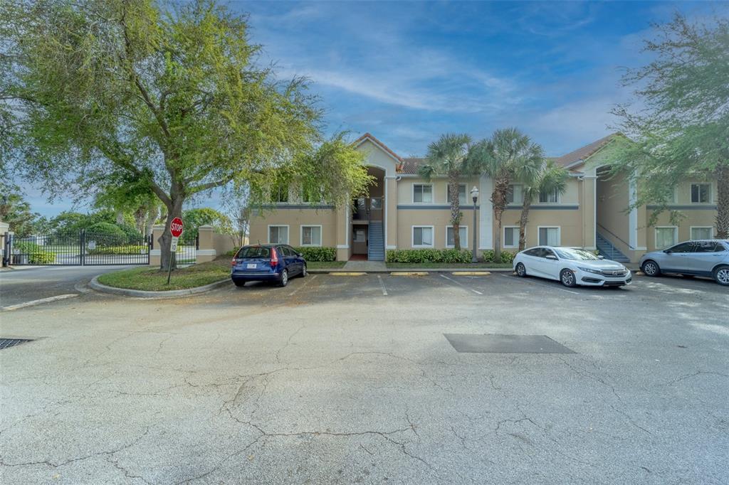 A two-story apartment building with a parking lot and palm trees in front — 13232 GALICIA STREET UNIT 101, ORLANDO, FL