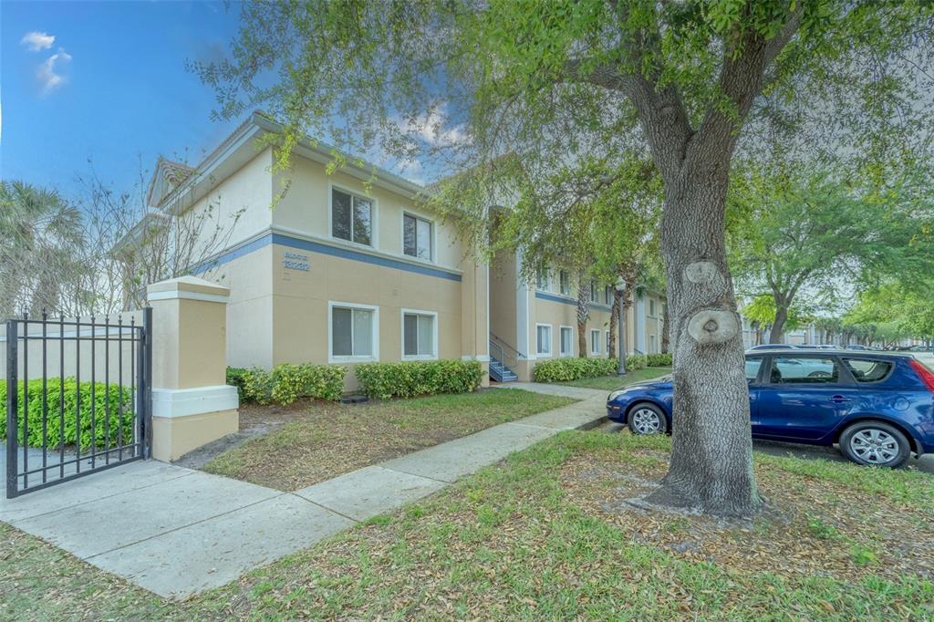 A two-story apartment building with beige stucco walls and a blue trim accent — 13232 GALICIA STREET UNIT 101, ORLANDO, FL