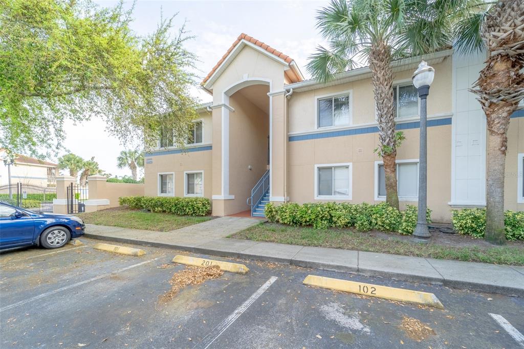 A two-story apartment building exterior with a blue car parked in front — 13232 GALICIA STREET UNIT 101, ORLANDO, FL