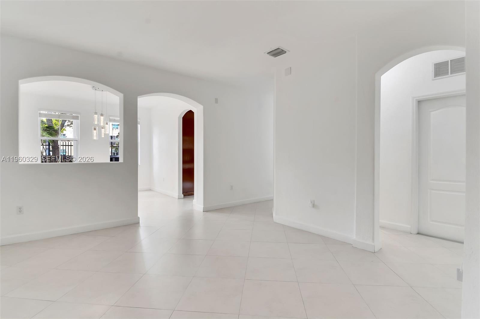 An interior view shows a white-walled room with arched doorways, tile flooring, and a window — 11321 NW 84th St, Doral FL 33178, DORAL, FL