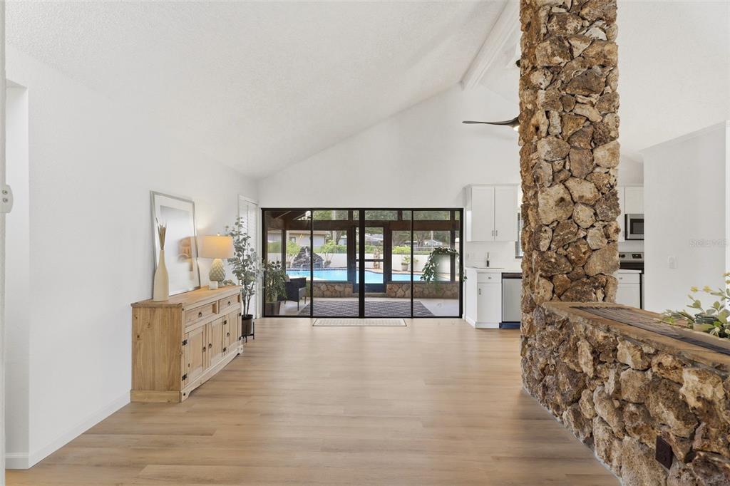 A living room with light wood floors, a stone pillar, and sliding doors to a pool — 4072 VANET COURT, ORLANDO, FL