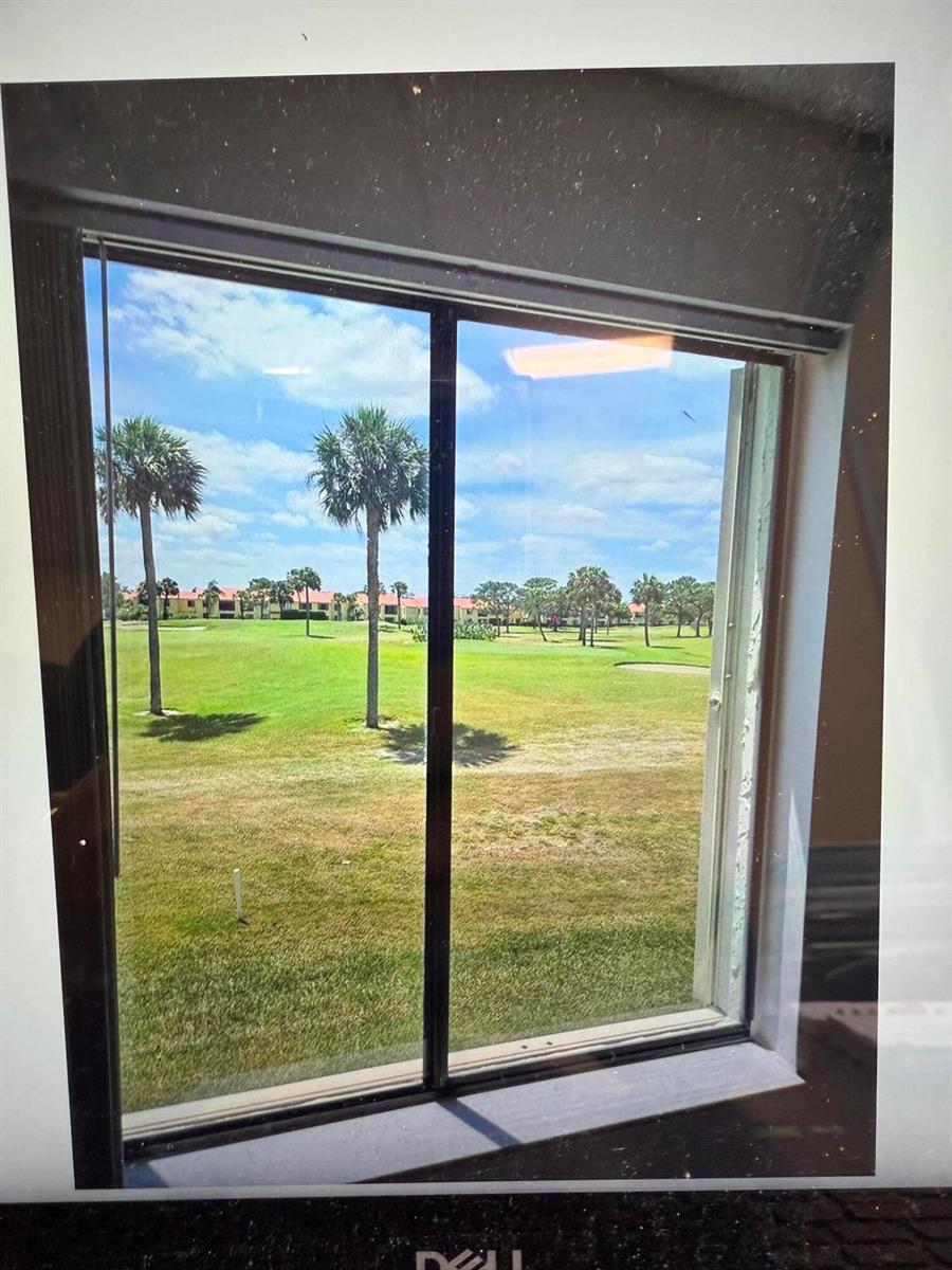 A view of a golf course with palm trees seen through a sliding glass door — 5403 SE Miles Grant Road, Stuart FL 34997, STUART, FL