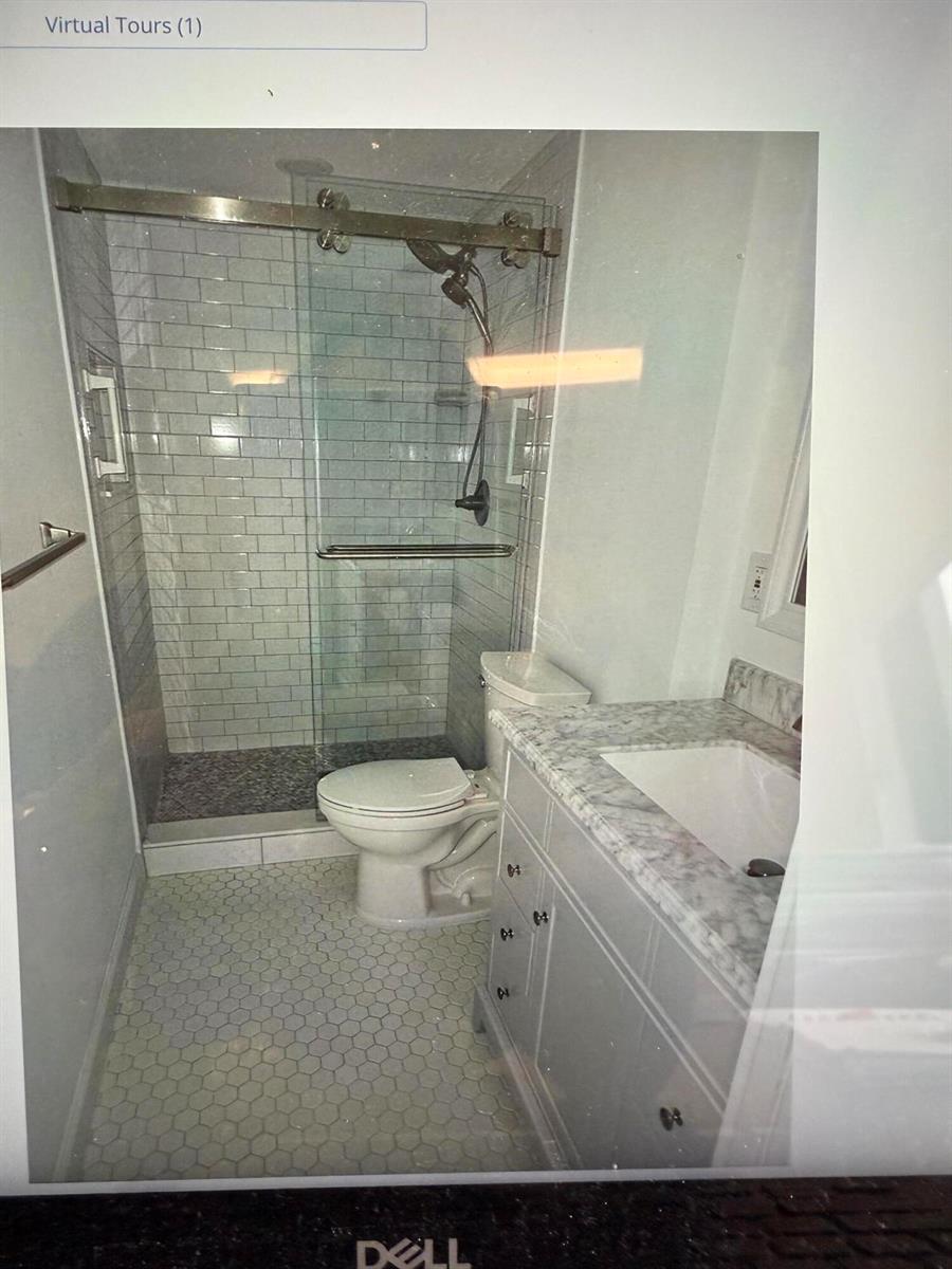 A bathroom features a glass-enclosed shower with subway tile, a toilet, and a marble vanity — 5403 SE Miles Grant Road, Stuart FL 34997, STUART, FL