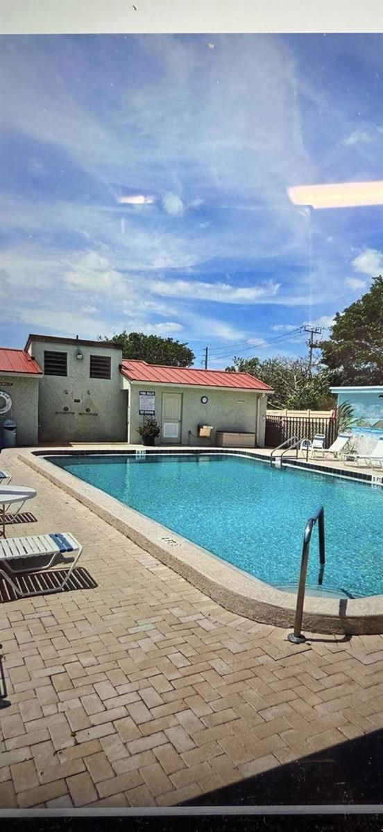 An outdoor swimming pool with a paved deck and a small building with a red roof — 5403 SE Miles Grant Road, Stuart FL 34997, STUART, FL