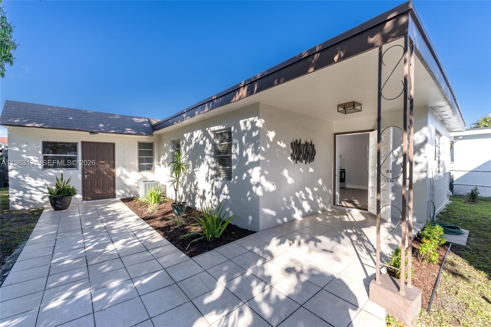 A white house exterior features a tiled patio, a brown door, and a covered entryway — 1631 SW 21st St, Miami FL 33145, MIAMI, FL