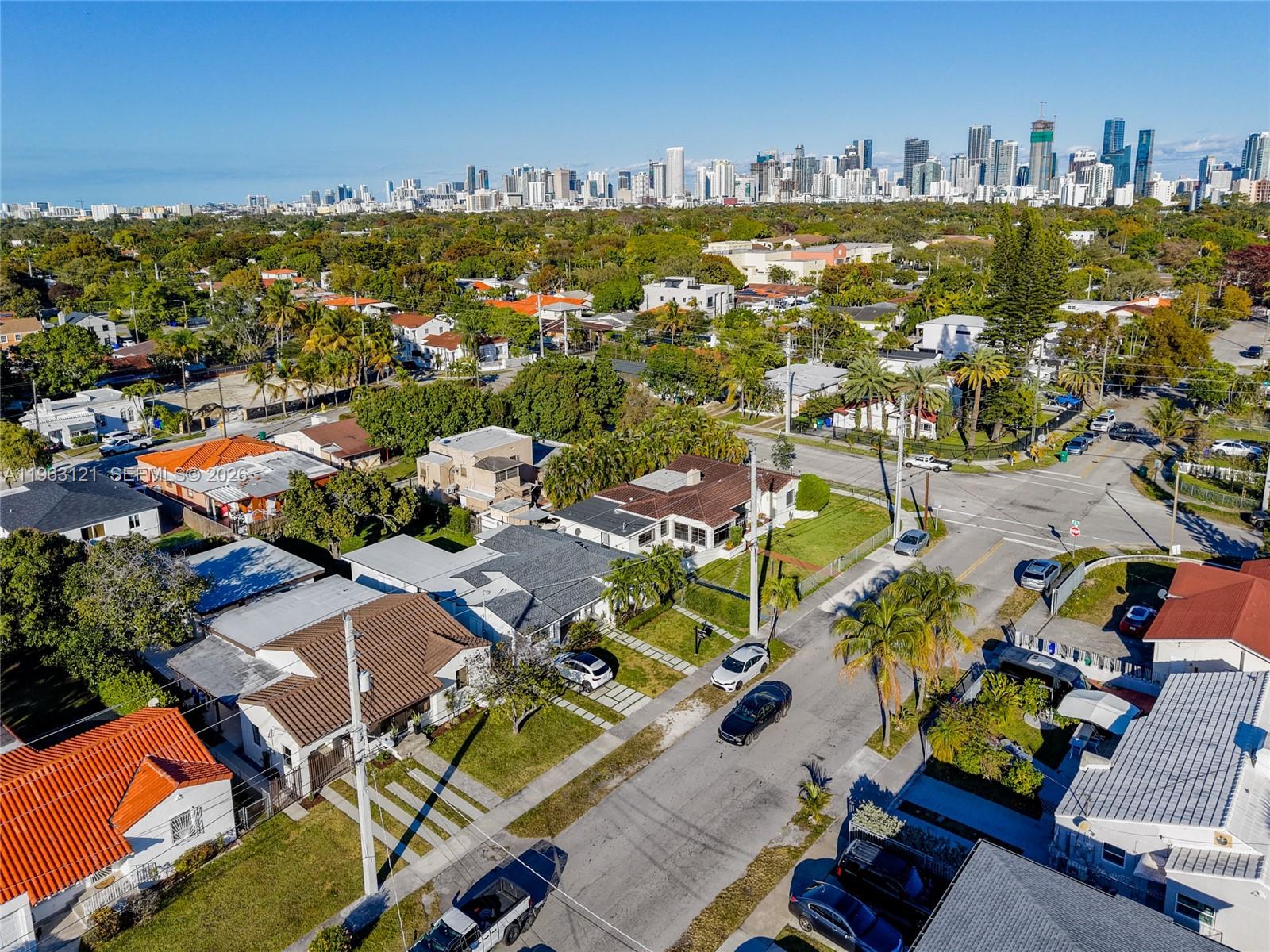 An aerial view shows a residential neighborhood with houses, streets, and a distant city skyline — 1631 SW 21st St, Miami FL 33145, MIAMI, FL