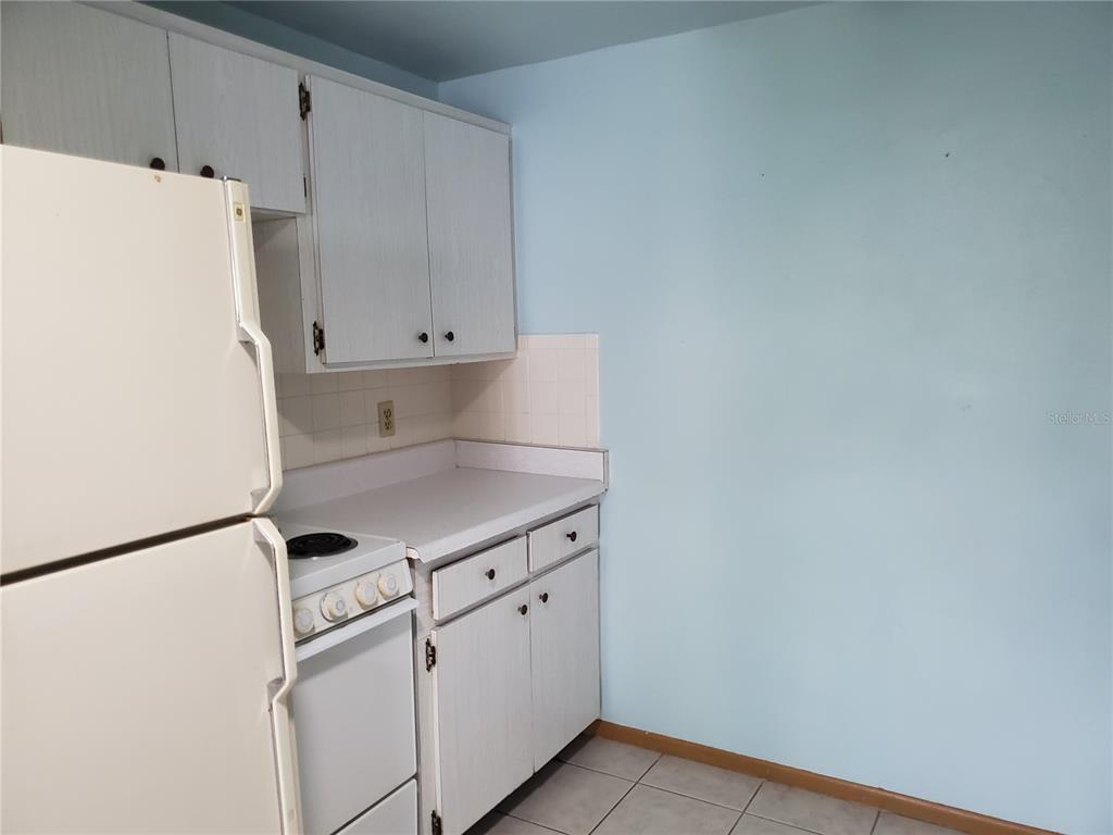 A kitchen features white cabinets, a white refrigerator, a stove, and light blue walls — 2021 PENNSYLVANIA AVENUE UNIT 5, ENGLEWOOD, FL
