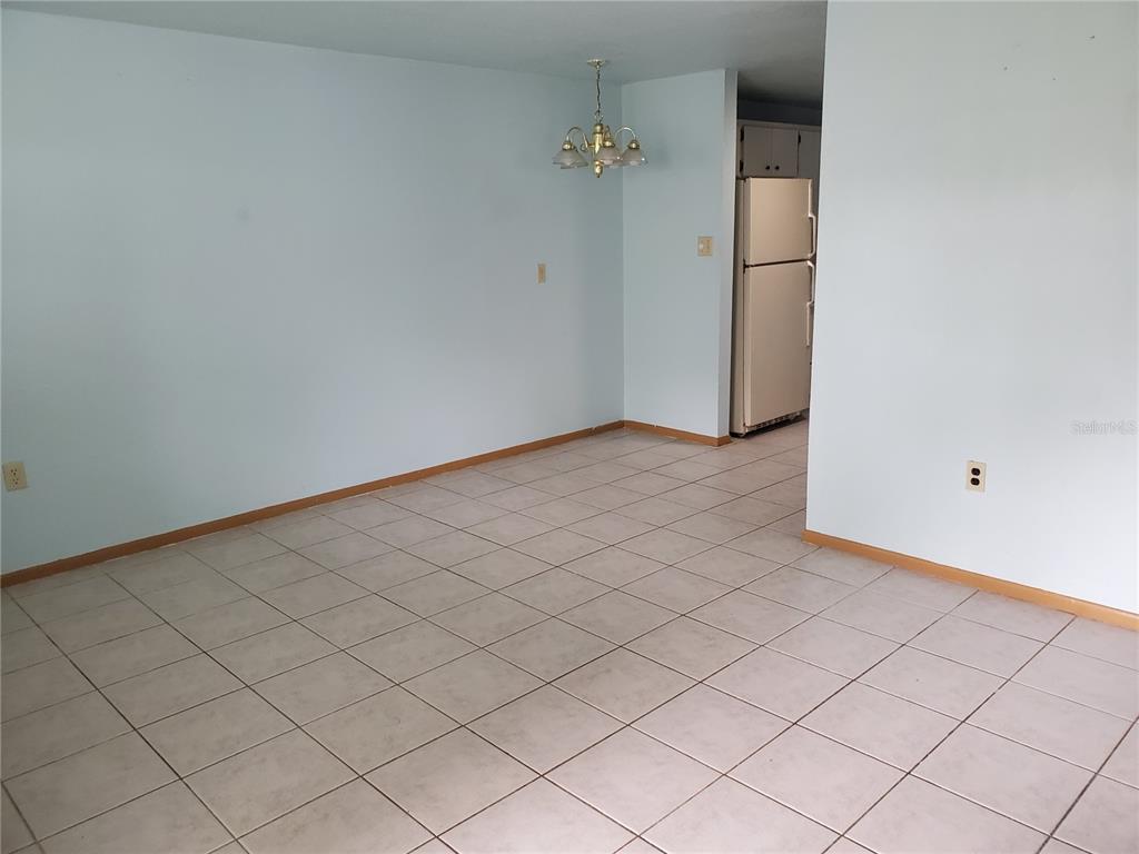 An empty dining area features light blue walls, tile flooring, and a brass chandelier — 2021 PENNSYLVANIA AVENUE UNIT 5, ENGLEWOOD, FL