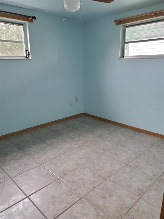 An empty room with light blue walls, tile flooring, and two windows with wooden rods — 2021 PENNSYLVANIA AVENUE UNIT 5, ENGLEWOOD, FL