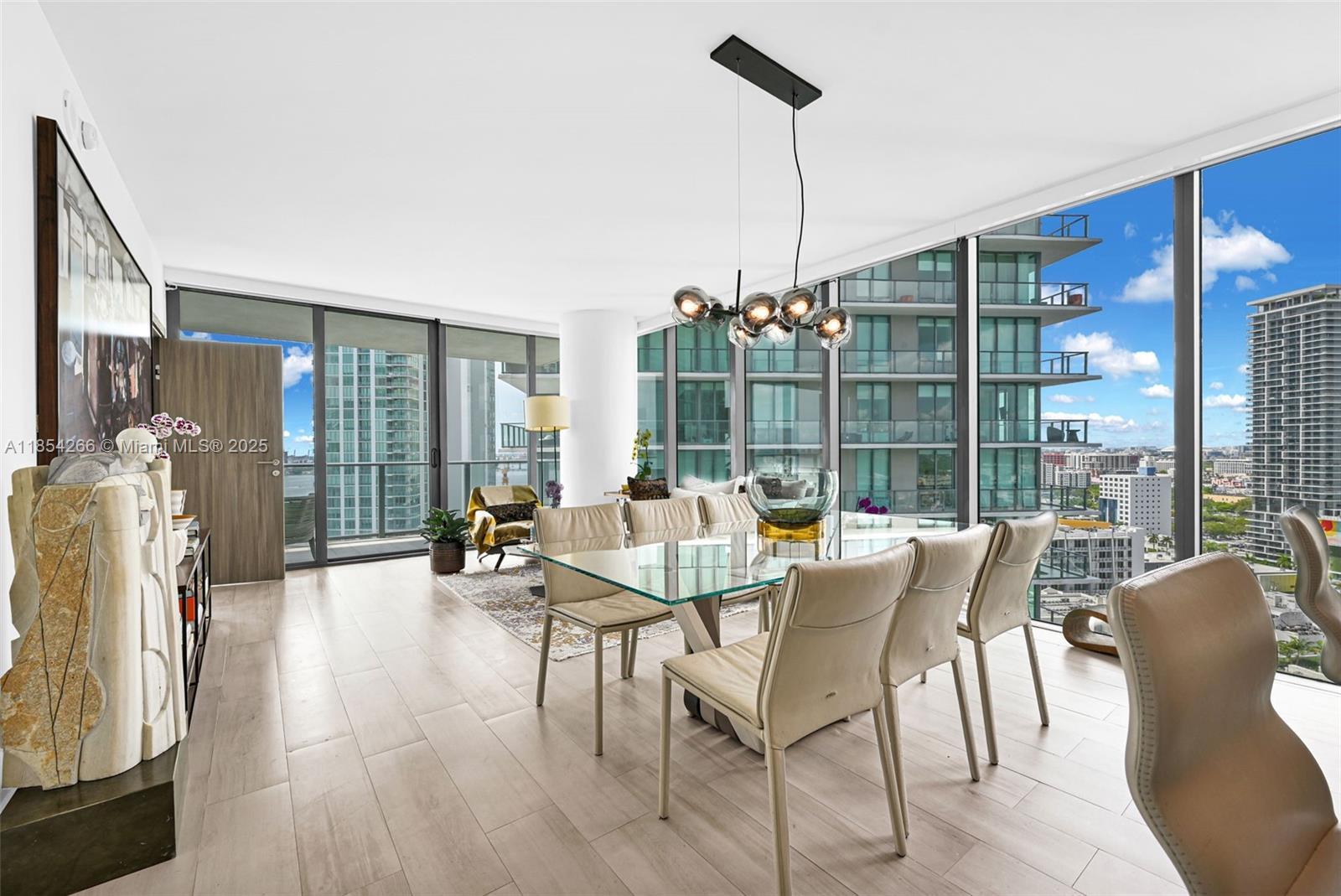 A modern dining area features a glass table, contemporary chairs, and floor-to-ceiling windows with city views — 650 NE 32nd St # 2201, Miami FL 33137, MIAMI, FL