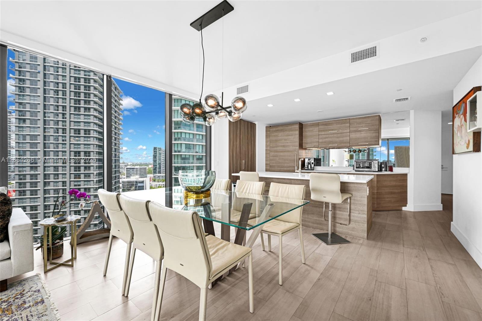 A modern dining area and kitchen feature a glass table, pendant lighting, and floor-to-ceiling windows — 650 NE 32nd St # 2201, Miami FL 33137, MIAMI, FL