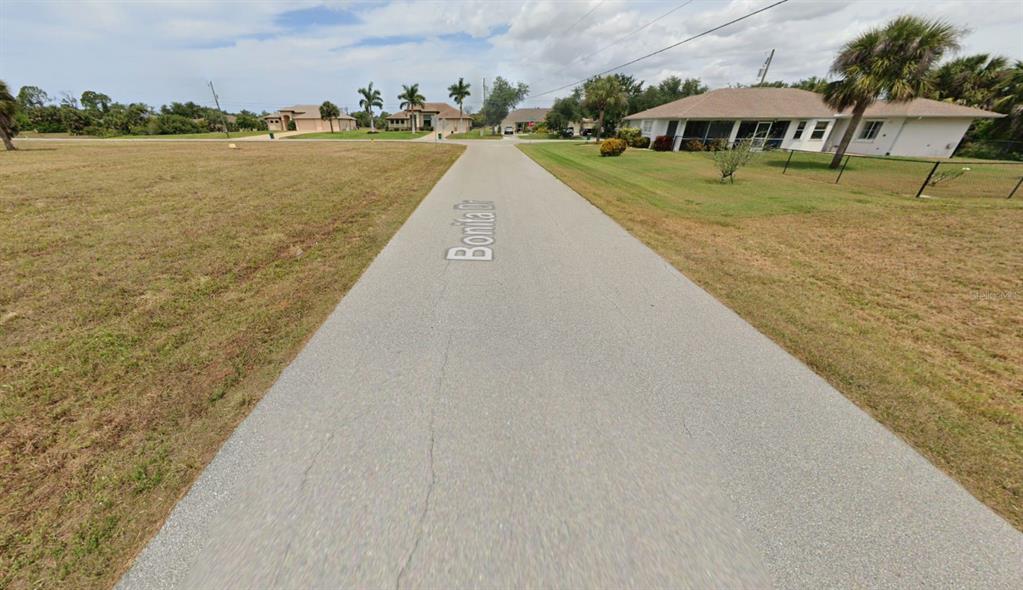 A paved street runs through a residential neighborhood with houses and palm trees — 103 BONITA DRIVE, ROTONDA WEST, FL