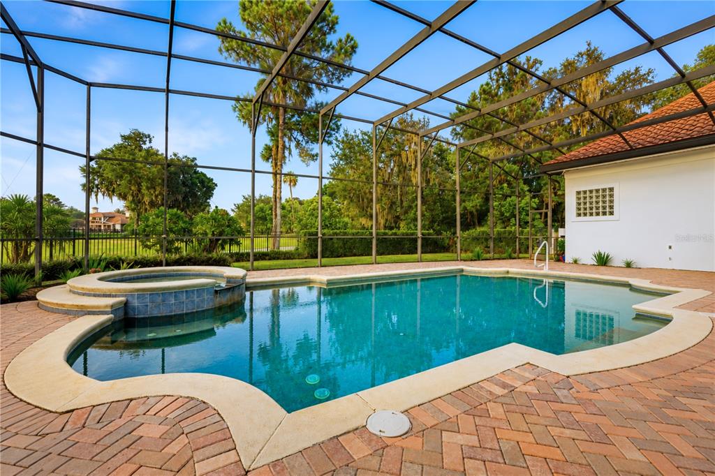 A living room features a fireplace, built-in cabinetry, a sofa, and large windows overlooking a pool — 3450 FOXMEADOW COURT, LONGWOOD, FL