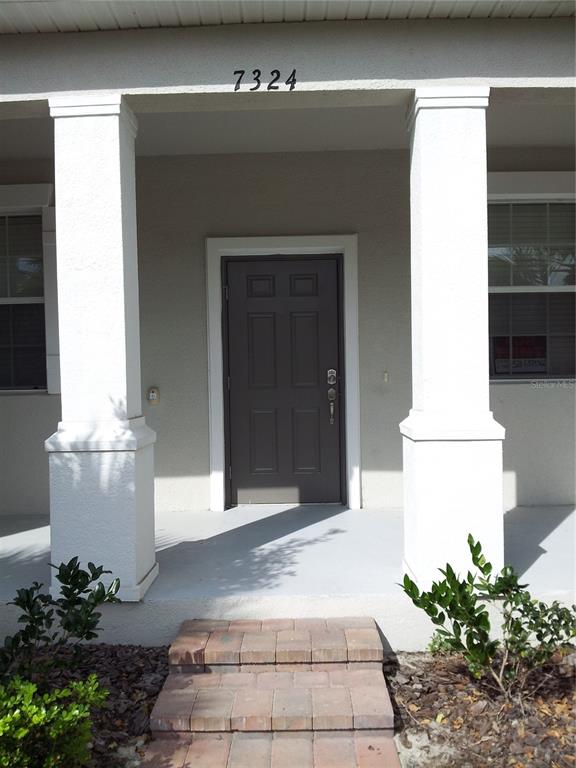 A front porch with two white columns leads to a dark brown entry door — 7324 ELLA LANE, WINDERMERE, FL