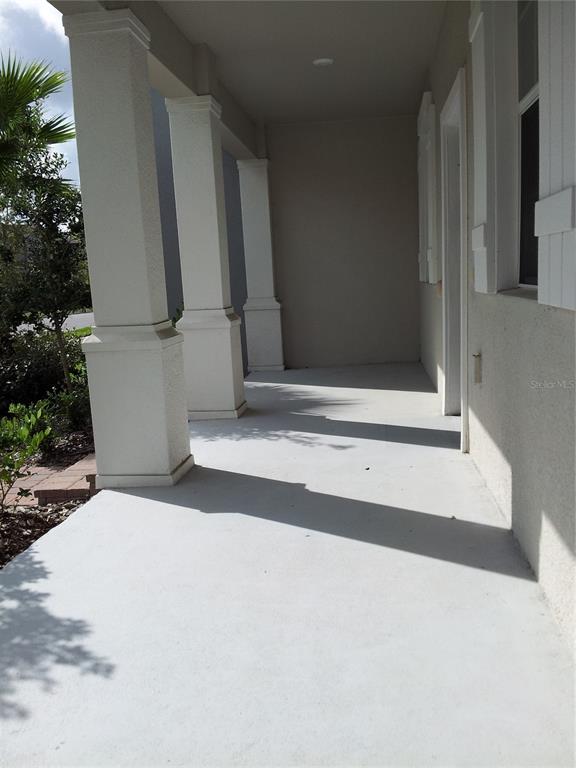 A covered front porch features white columns, a light-colored concrete floor, and stucco walls — 7324 ELLA LANE, WINDERMERE, FL