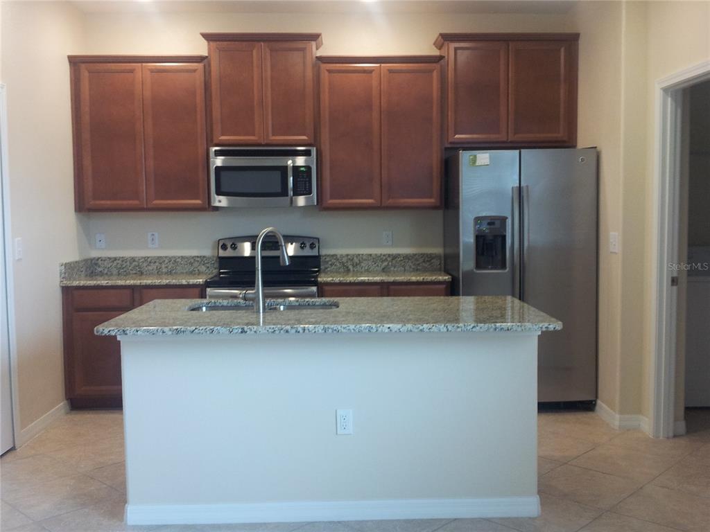 A kitchen features wood cabinets, granite countertops, stainless steel appliances, and a central island — 7324 ELLA LANE, WINDERMERE, FL