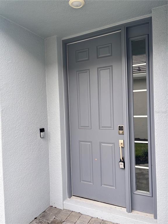 A gray front door with a side window and a smart doorbell on the wall — 16117 ISOLA PLACE, BRADENTON, FL