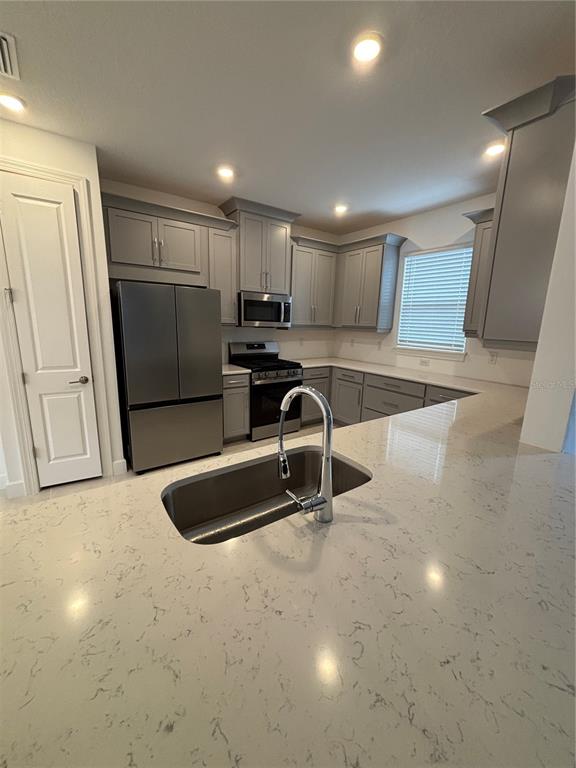 A kitchen with grey cabinets, stainless steel appliances, and a white quartz island countertop — 16117 ISOLA PLACE, BRADENTON, FL
