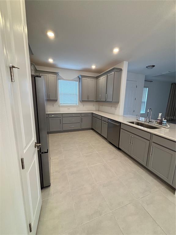 A kitchen features gray cabinetry, stainless steel appliances, and light-colored tile flooring — 16117 ISOLA PLACE, BRADENTON, FL