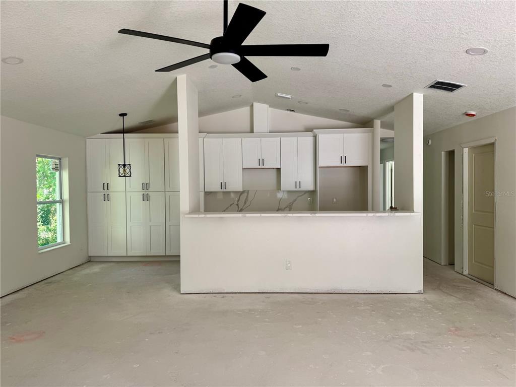 A bright, empty room features white walls, light wood-look flooring, a ceiling fan, and windows — 2017 E SEWARD STREET, TAMPA, FL