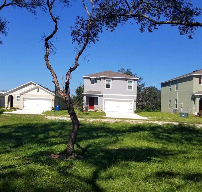 A two-story house with a white garage sits between two other homes on a sunny day — 1671 ROSYDALE CIRCLE, DAVENPORT, FL