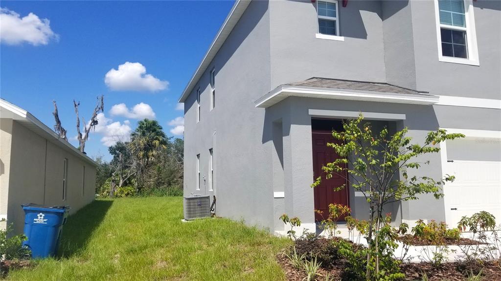 A two-story gray house features a red front door and a side yard — 1671 ROSYDALE CIRCLE, DAVENPORT, FL