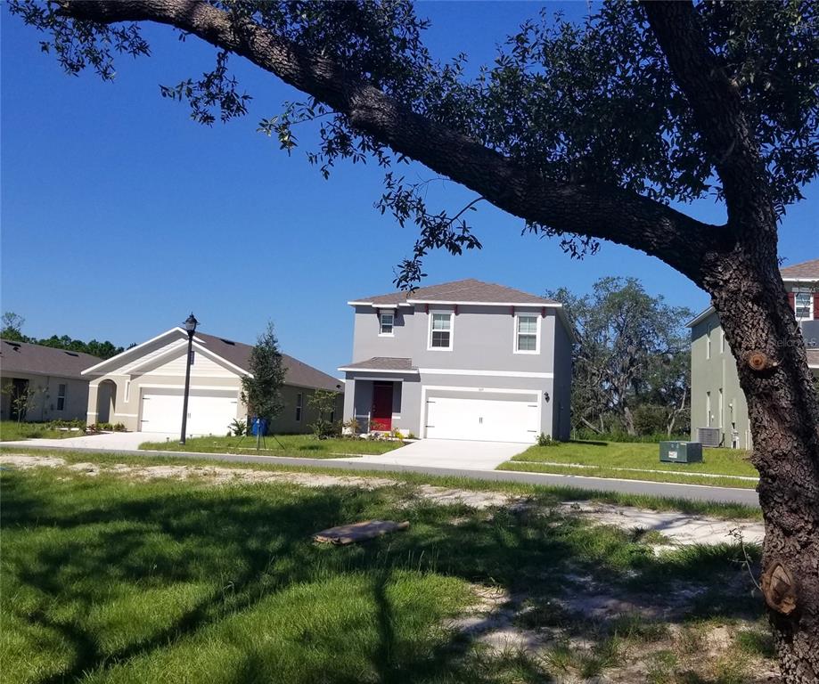 A two-story gray house with a red front door and white garage sits on a street — 1671 ROSYDALE CIRCLE, DAVENPORT, FL