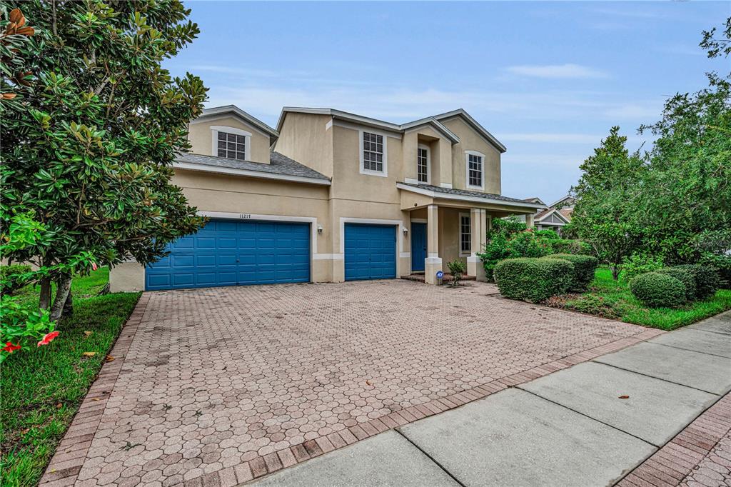 A two-story house with a beige stucco exterior, blue garage doors, and a paved driveway — 11217 LAUREL BROOK COURT, RIVERVIEW, FL