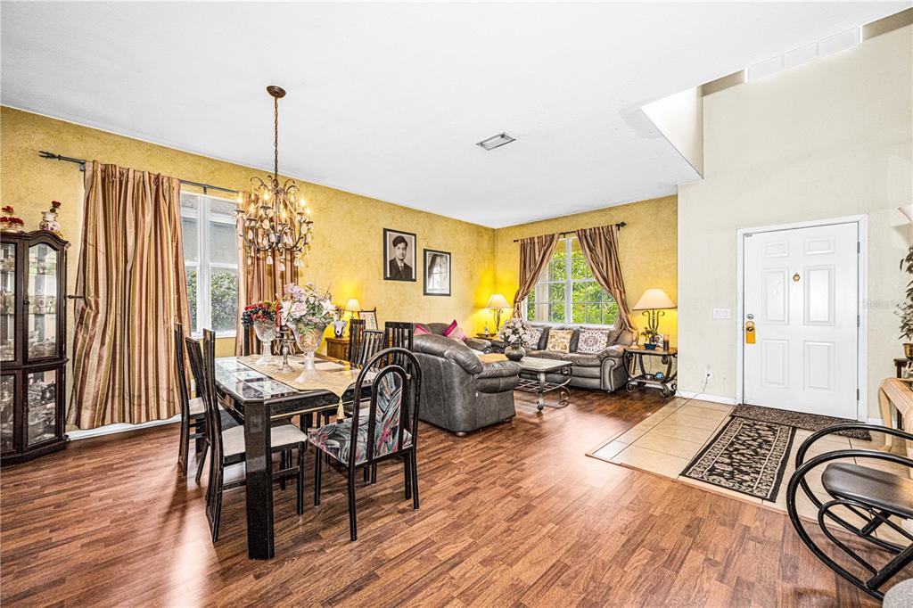 A dining and living area features wood-look flooring, yellow walls, and a white front door — 11217 LAUREL BROOK COURT, RIVERVIEW, FL