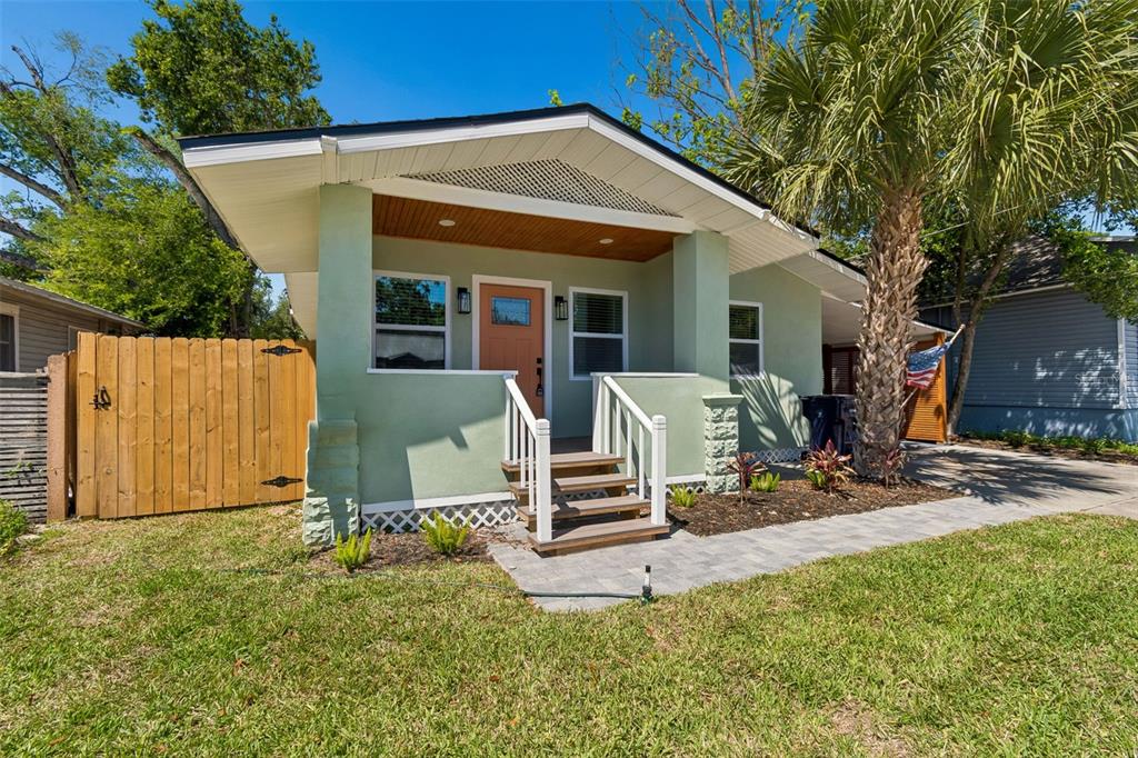 A light green bungalow with a front porch, wooden steps, and a palm tree — 106 E FERN STREET, TAMPA, FL