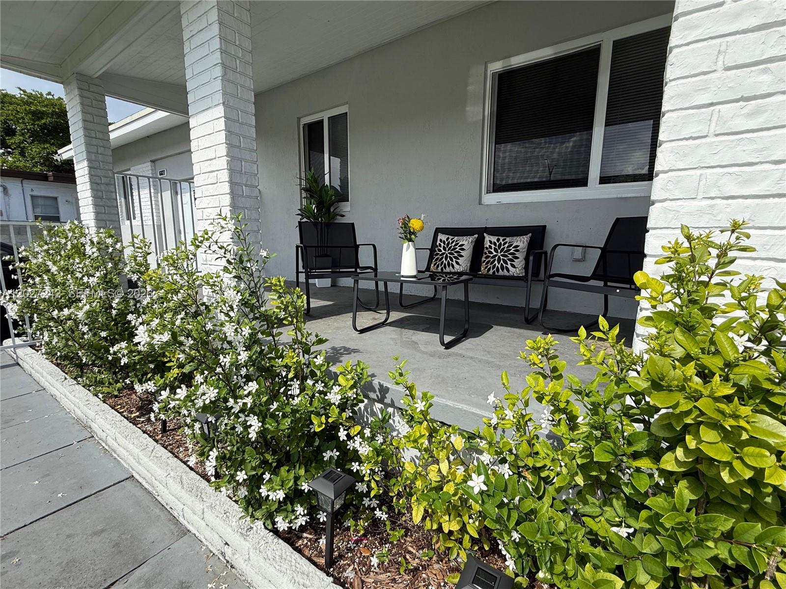 A covered front porch features white brick columns, a concrete floor, and outdoor seating — 6825 NW 5th Ct # 0, Miami FL 33150, MIAMI, FL