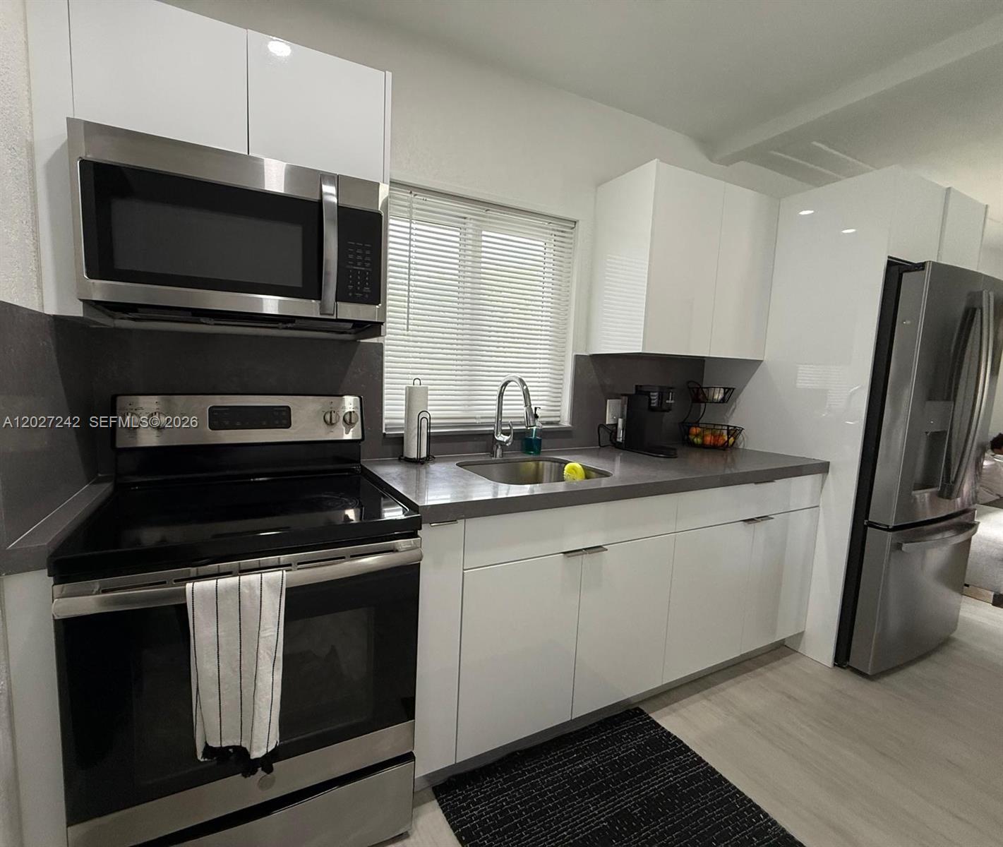 A kitchen features white cabinets, stainless steel appliances, and gray countertops — 6825 NW 5th Ct # 0, Miami FL 33150, MIAMI, FL