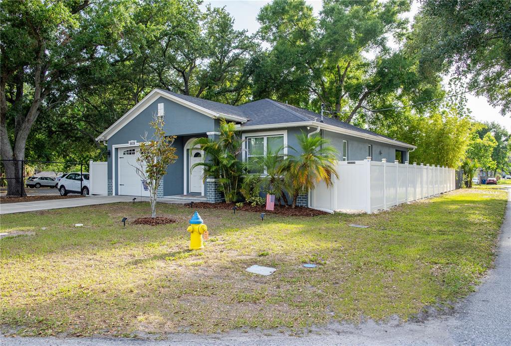 A blue single-story house with a white fence and a fire hydrant in the yard — 8608 N MITCHELL AVENUE, TAMPA, FL