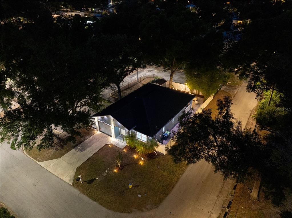 An aerial night view of a single-story house with a driveway and surrounding trees — 8608 N MITCHELL AVENUE, TAMPA, FL