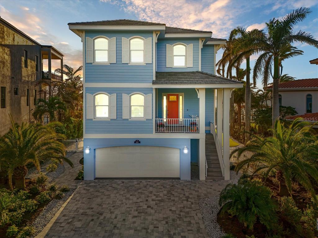 A light blue, three-story coastal home features a two-car garage and an elevated front entrance — 12917 42ND TERRACE W, CORTEZ, FL