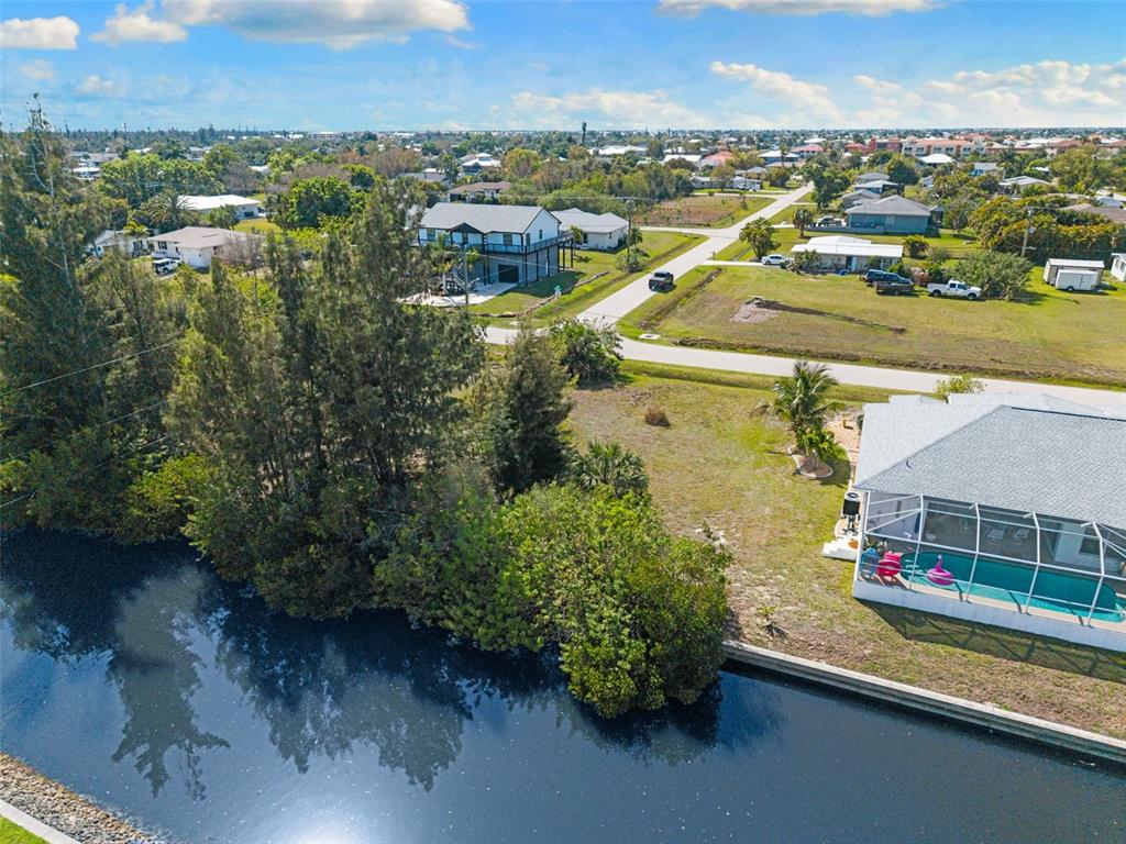 An aerial view shows a canal, a house with a pool cage, and surrounding neighborhood lots — 2524 LARKSPUR DRIVE, PUNTA GORDA, FL