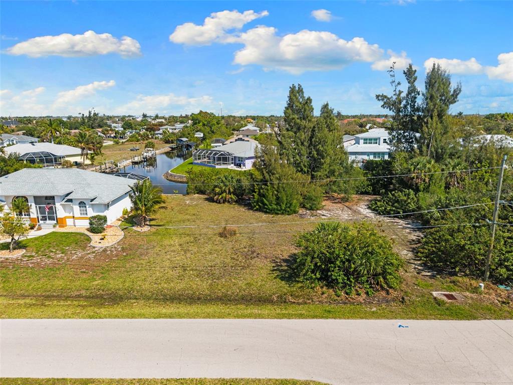 An aerial view shows a vacant grassy lot situated next to a house and canal — 2524 LARKSPUR DRIVE, PUNTA GORDA, FL