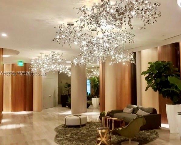 A modern lobby features large, sparkling, tree-like chandeliers, wood-paneled walls, and a seating area — 488 NE 18th St # 705, Miami FL 33132, MIAMI, FL