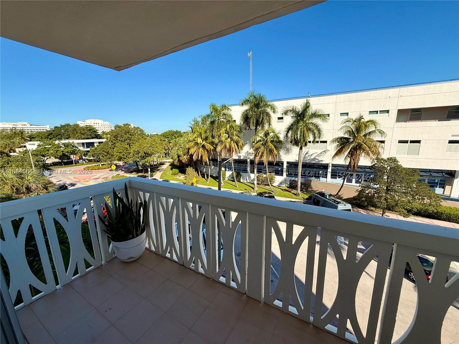 A balcony with a decorative white railing overlooks a parking lot and palm trees — 4142 N Jefferson Ave # 4D, Miami Beach FL 33140, MIAMI BEACH, FL