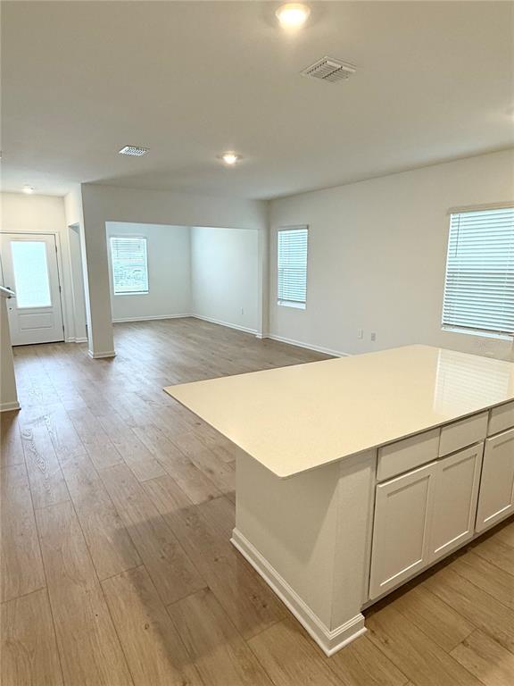 A kitchen island with white cabinets and a light countertop sits in an open-concept room — 5107 LOYALTY DRIVE, ST CLOUD, FL