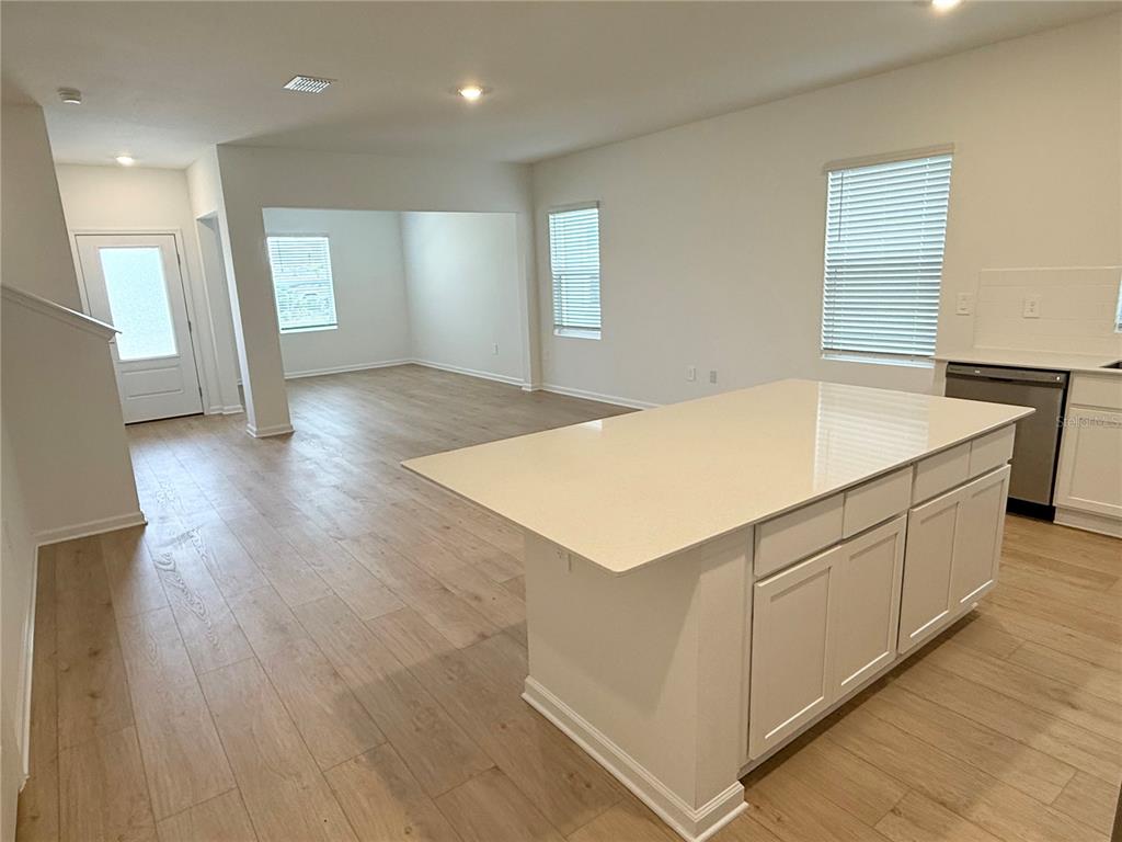 A kitchen island with white cabinets and quartz countertops sits in an open-concept living area — 5107 LOYALTY DRIVE, ST CLOUD, FL
