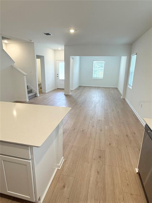 An open-concept living area features light wood-look flooring and a kitchen island with white cabinets — 5107 LOYALTY DRIVE, ST CLOUD, FL